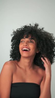 Saçları kıvırcık ve parlak makyajlı gülümseyen genç modelin dikey portresi. Yavaş Hareket, Kapat.