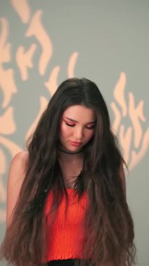 Uzun siyah saçlı ve parlak makyajlı genç bir mankenin dikey portresi. Yavaş Çekim, Kapat, Stüdyo Çekimi.