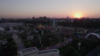 Bir dron lunaparkın üzerinde atlı karınca ve dönme dolap ile uçuyor. Hava görünümü.