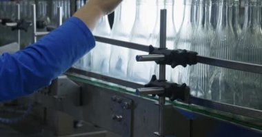 Bir işçi, cam şişeleri eliyle taşıyıcının üzerinde hareket ederken kontrol eder. Yavaş Hareket.