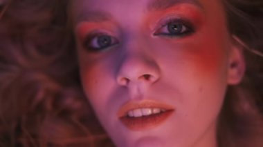 Dallardan, yapraklardan ve mısır başaklarından oluşan sonbahar kıyafeti içindeki genç bir kadının dağınık elmaların arasında çimlerin üzerinde uçarken çekilmiş yakın plan fotoğrafı. Yavaş Hareket.