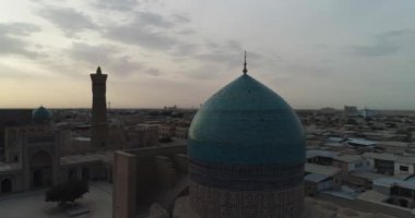 Bir İHA, Poi-Kalon mimari kompleksinin üzerinde uçuyor. Özbekistan 'ın eski Buhara kentindeki bir evin arka planında. Bulutlu bir gün. Hava Görünümü.