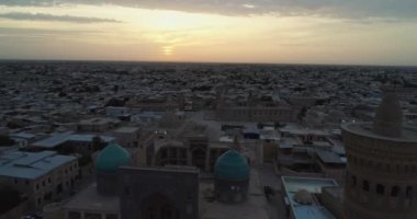 Özbekistan 'ın Buhara kentindeki eski evler arasında Poi-Kalon mimari kompleksinin üzerinde bir dron uçuyor. Erkenden bulutlu bir sabah. Hava Görünümü.