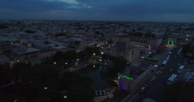 Eski Buhara, Özbekistan 'daki evlerle çevrili antik bir Lyab-i Hauz kompleksinin üzerinde bir İHA uçuyor. Bulutlu bir gece. Hava Görünümü.