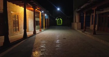 İnsansız hava aracı eski sütunların arasında antik şehrin gece sokaklarında uçuyor. Buhara, Özbekistan, Havadan görünüm.