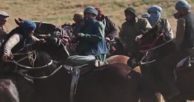 Taşkent, Özbekistan - 210 2023: Ata binmiş bir grup adam sonbahar tepelerinde şarap tulumuyla Asya oyunu oynuyor. Yavaş Hareket.
