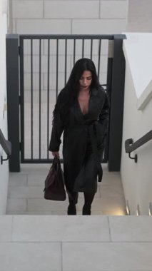 Uzun yağmurluklu esmer kadın merdivenleri çıkıyor. Yavaş Hareket