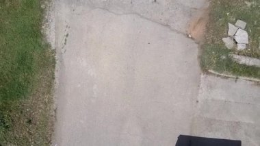 İnsansız hava aracı, ağaçların arasındaki asfalt bir yola iniyor.