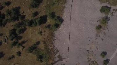 İnsansız hava aracı çalılar ve yeşilliklerle kaplı dağlara iniyor. Bulutlu bir yaz günü. Hava Görünümü