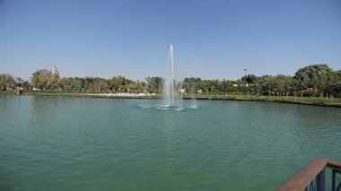 Şehir gölünün üzerinde çeşmelere bakan iskele boyunca bir yürüyüş. Güneşli bir yaz günü. Yavaş Hareket