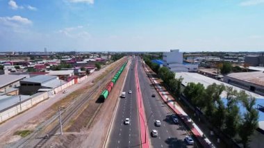 Tarlalar ve ağaçlar arasında otoban boyunca giden bir trenin üzerinde bir dron. Güneşli bir yaz günü. Hava Görünümü