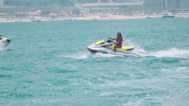 Açık denizlerde jet ski üzerinde can yeleği giymiş esmer bir kadın. Yavaş çekim