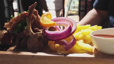 Şef pişmiş et, soğan, otlar, domatesler ve sebzelerle servis edilen ahşap bir tahtayı gösteriyor. Kapat, Yavaş Hareket.