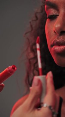 Makyöz, fotoğraf stüdyosunda genç ve çekici bir mankenin dudaklarına ruj sürüyor. Yavaş Hareket.