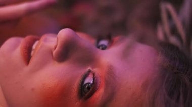 Dallardan, yapraklardan ve mısır başaklarından oluşan sonbahar kıyafeti içindeki genç bir kadının dağınık elmaların arasında çimlerin üzerinde uçarken çekilmiş yakın plan fotoğrafı. Yavaş Hareket.