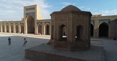 İnsansız hava aracı antik Lyab-i Hauz kompleksinin avlusunda turistlerle birlikte uçuyor. Eski Buhara, Özbekistan. Hava Görünümü.