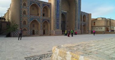 İnsansız hava aracı, antik Lyab-i Hauz kompleksinin ana kapısının yakınında uçuyor. Turist grupları kapının yanında. Eski Buhara, Özbekistan. Hava Görünümü.