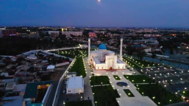 Aydınlanmış bir camide gece bir dron uçuyor. Arka planda bulutlu bir gökyüzü. Hava Görünümü.