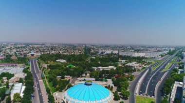 İnsansız hava aracı hareket halindeki arabalarla şehrin yollarında ve otoyollarında uçuyor. Bulutlu bir yaz günü. Hava Görünümü.