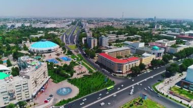 İnsansız hava aracı hareket halindeki arabalarla şehrin yollarında ve otoyollarında uçuyor. Bulutlu bir yaz günü. Hava Görünümü.