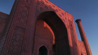 Özbekistan, Semerkant 'taki Bibi-Khanym Camii yakınlarında bir İHA uçuyor. Bina pembe şafak ışığı ile aydınlatılır. Bulutsuz bir sabah. Hava Görünümü.