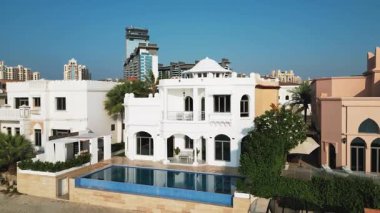 İHA mavi bulutsuz bir gökyüzünün arka planında yüzme havuzu olan özel bir Arap villasının etrafında uçuyor. Hava Görünümü