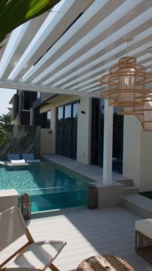 Güneşli bir günde Dubai 'de özel bir villanın arka bahçesinde küçük bir yüzme havuzu ve kanepesi var. Dışarıda ağır çekim.