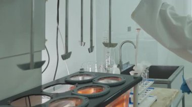 Koruyucu giysiler içindeki laboratuvar teknisyeni laboratuardaki otomatik karıştırıcıdan kimyasal örnekler alıyor. Kapat, Yavaş Hareket.