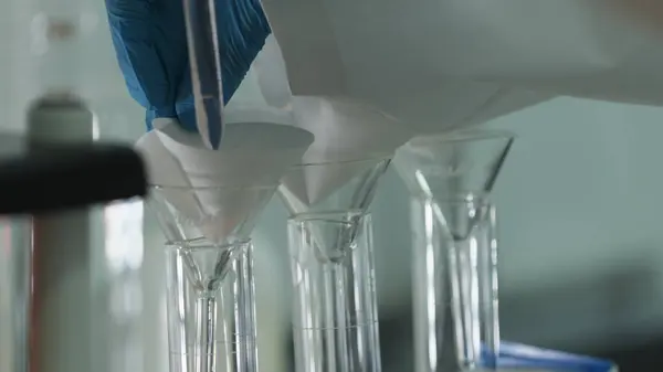 Taşkent, Özbekistan - 11 10 2023: Sıvıyı filtreden geçirerek cam laboratuarının mucizesine dönüştürmek. Kimyasal laboratuvar, ağır çekim..