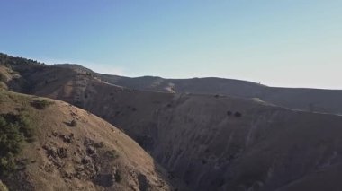 Bir dron, bir nehir ile dağ kanyonunun üzerinden uçuyor. Güneş dağların üzerinden doğuyor. Bulutsuz bir yaz sabahı. Hava Görünümü.