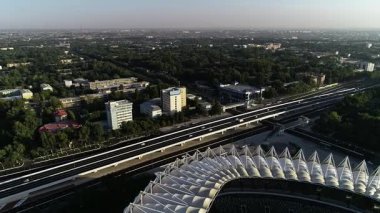 İHA, şehir merkezindeki büyük bir stadyumun içinden uçuyor. Güneşli bir yaz günü. Hava görünümü.