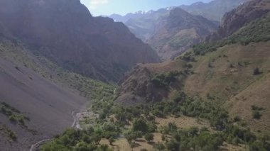 Yeşillik ve çalılarla kaplı dağların tepesindeki bir dron. Bulutlu bir yaz günü. Hava görünümü.