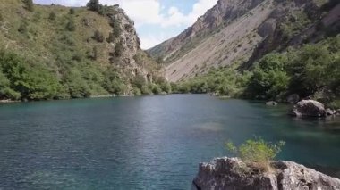 Bir dron dağ gölünün sularında bir vadide uçuyor. Bulutlu bir yaz günü. Hava Görünümü