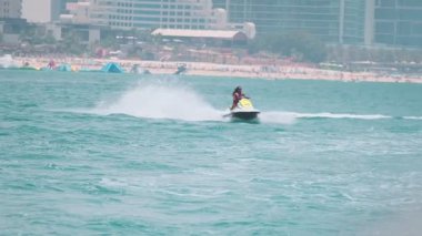 Açık denizlerde jet ski üzerinde can yeleği giymiş esmer bir kadın. Yavaş çekim