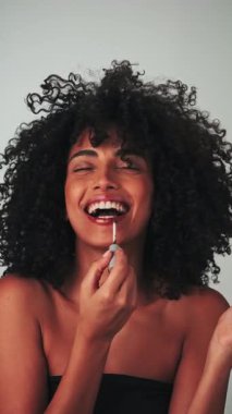 Kasvetli saçı ve parlak makyajı olan genç bir mankenin dikey portresi. Rujlu boya küpleri. Yavaş Çekim, Yakın Çekim. Stüdyo çekimi.