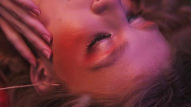 Dallardan, yapraklardan ve mısır başaklarından oluşan sonbahar kıyafeti içindeki genç bir kadının dağınık elmaların arasında çimlerin üzerinde uçarken çekilmiş yakın plan fotoğrafı. Yavaş Hareket.