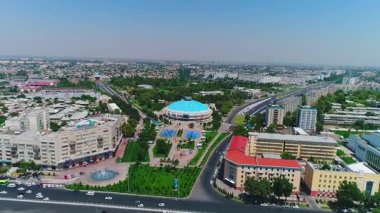 İnsansız hava aracı hareket halindeki arabalarla şehrin yollarında ve otoyollarında uçuyor. Bulutlu bir yaz günü. Hava Görünümü.