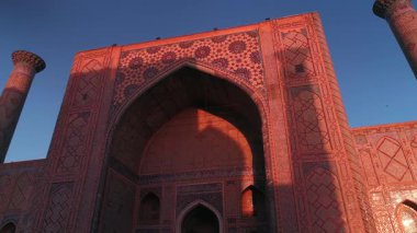 Özbekistan, Semerkant 'taki Bibi-Khanym Camii yakınlarında bir İHA uçuyor. Bina pembe şafak ışığı ile aydınlatılır. Bulutsuz bir sabah. Hava Görünümü.