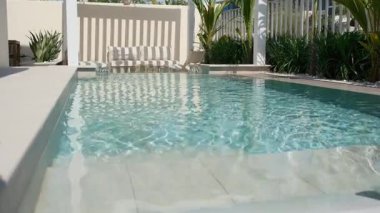 Güneşli bir günde Dubai 'de özel bir villanın arka bahçesinde küçük bir yüzme havuzu ve kanepesi var. Dışarıda ağır çekim.