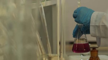 Laboratuvarda cam eşyalar ile çalışan koruyucu giysili laboratuvar teknisyenlerinin elleri. Kapat, Yavaş Hareket.