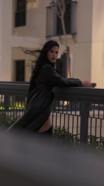 Saçları rüzgarda uçuşan, akşam yürüyüşünde uzun bir yağmurlukla genç bir kadın. Yavaş Hareket