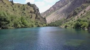 Bir dron dağ gölünün sularında bir vadide uçuyor. Bulutlu bir yaz günü. Hava Görünümü