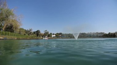 Şehir gölünde turistli tekneler fıskiyelerin etrafında yüzüyor. Güneşli yaz günü Yavaş Hareket