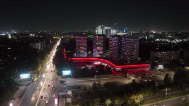 Geceleri Taşkent 'te, aydınlık sokaklara ve yüksek binalara bakan bir dron. Bulutsuz Yaz Gecesi. Hava Görünümü