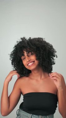 Saçları kıvırcık ve parlak makyajlı gülümseyen genç modelin dikey portresi. Yavaş Hareket, Kapat.