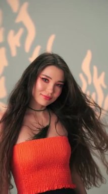 Rüzgarda savrulan uzun saçlı ve parlak makyajlı genç bir kadının dikey portresi. Yavaş Çekim, Kapat, Stüdyo Çekimi.