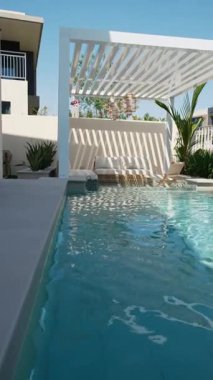 Güneşli bir günde Dubai 'de özel bir villanın arka bahçesinde küçük bir yüzme havuzu ve kanepesi var. Dışarıda ağır çekim.