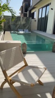 Güneşli bir günde Dubai 'de özel bir villanın arka bahçesinde küçük bir yüzme havuzu ve kanepesi var. Dışarıda ağır çekim.