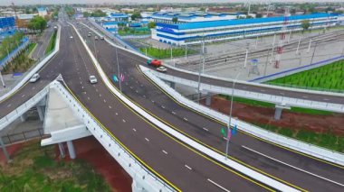 İnsansız hava aracı hareket halindeki arabalarla şehrin yollarında ve otoyollarında uçuyor. Bulutlu bir yaz günü. Hava Görünümü.