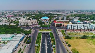 İnsansız hava aracı hareket halindeki arabalarla şehrin yollarında ve otoyollarında uçuyor. Bulutlu bir yaz günü. Hava Görünümü.